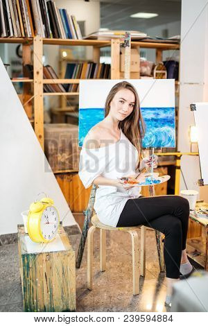 Painting Process At Workshop . Young Professional Female Artist Looking At Camera, Painting A Pictur