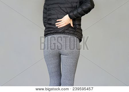 Close-up View Of A Young Woman With Pain In Kidneys Isolated On Gray Background. Young Woman With Ba