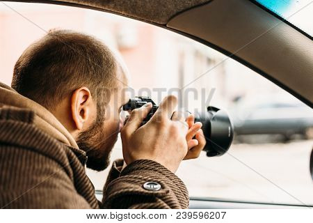 Private Detective Or Reporter Or Paparazzi Sitting In Car And Taking Photo With Professional Camera,