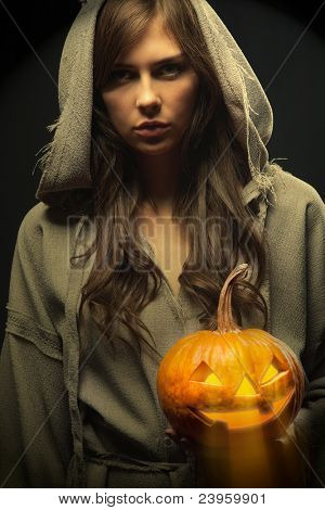 Köntös keresztkötés körül a fejét, ragyogó halloween tök gazdaság nő