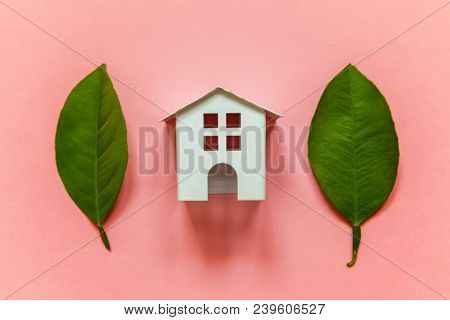 Miniature Toy Model House With Green Leaves On Pink Pastel Colourful Trendy Backgdrop. Eco Village, 