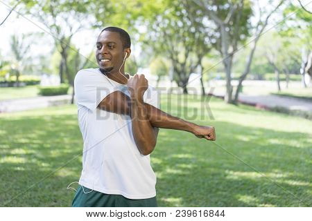 Smiling Sporty Black Man Listening To Music And Doing Morning Exercises In Park. Young Afro American