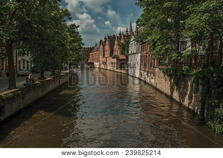Wooded Gardens And Brick Buildings On The Canal Edge In A Sunny Day At Bruges. With Many Canals And 