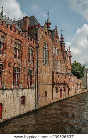 Old Brick Buildings On The Canal Edge In A Sunny Day At Bruges. With Many Canals And Old Buildings, 