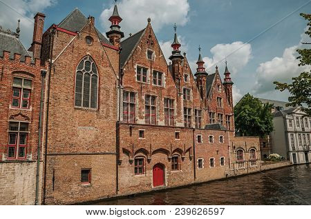 Old Brick Buildings On The Canal Edge In A Sunny Day At Bruges. With Many Canals And Old Buildings, 