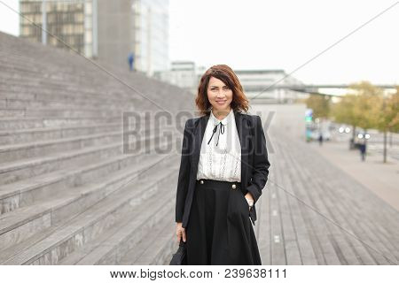 European Businesslady Standing On Stairs Outside In High Buildings Background. Concept Of Profession