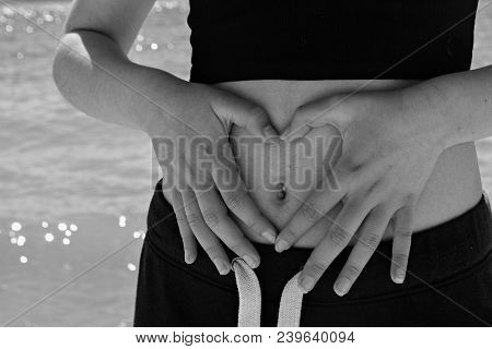 Close-up Of A Slim Woman With A Thin Waist In Black Panties And Black Short Top Making A Heart With 