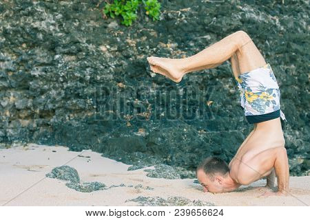 Handsome Man Doing Yoga Near The Beach With Blue Sky And Sea Background. Relaxing And Healthy Lifest