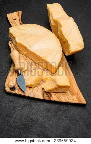 Pieces Of Parmesan Or Parmigiano Hard Cheese And Grapes On Wooden Cutting Board