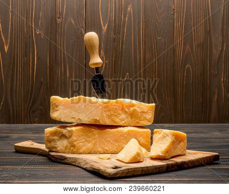Pieces Of Parmesan Or Parmigiano Hard Cheese And Grapes On Wooden Cutting Board