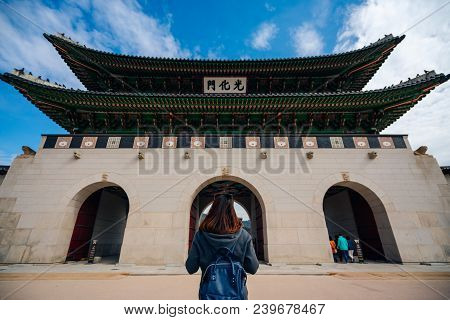 Young Asian Woman Traveler With Backpack Traveling Into The Gyeongbokgung Palace  With Blue Sky And