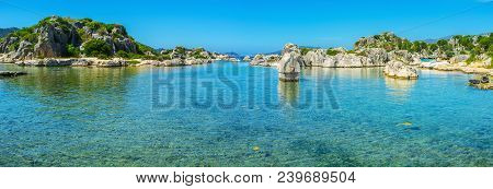 The Ancient Lycian Sarcophagus In Water, Surrounded By Rocks At The Shore Of Ancient Simena Village,