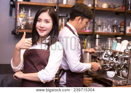 Asian Women Barista Smiling And Looking To Camera In Coffee Shop Counter.  Barista Female Working At