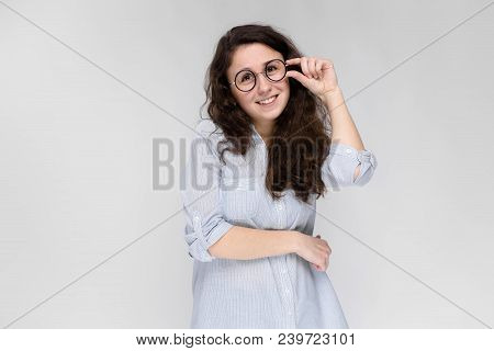 Young Girl Holds Her Hand Glasses. The Girl Is Smiling. The Girl Is Looking At The Camera.