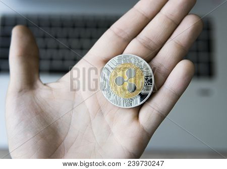 Ripple Coin On A Laptop Keyboard Closeup On A Miner Hand. Blockchain Mining. Digital Money And Virtu