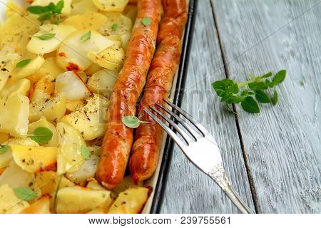 Tasy Baked Potato Slices With Fried Munich Sausages With Basil Leaves On A Baking Sheet