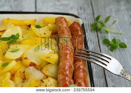 Tasy Baked Potato Slices With Fried Munich Sausages With Basil Leaves On A Baking Sheet