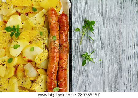 Tasy Baked Potato Slices With Fried Munich Sausages With Basil Leaves On A Baking Sheet