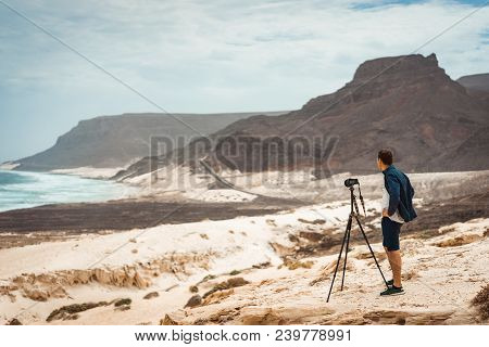 Photographer With Camera In Desert Admitting Unique Landscape Of Sand Dunes Volcanic Cliffs On The A