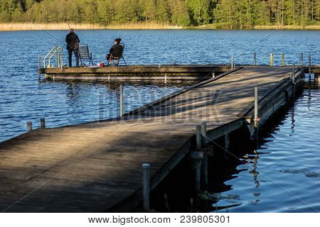 Fish Fishing At A Lake In Central Europe. Anglers Fishing On The Pier.
