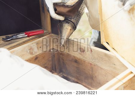 Beekeeper Is Working With Bees And Beehives On The Apiary.bee Smoker Is Used - Beekeepers Tool To Ke