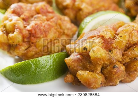 Close Up View Of Favourite Indian Appetizer, Indian Bhajias Or Bhajis, On A White Plate With Sliced 