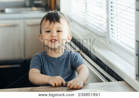 The Little Boy In The Kitchen Eagerly Eating Rice With A Spoon Independently