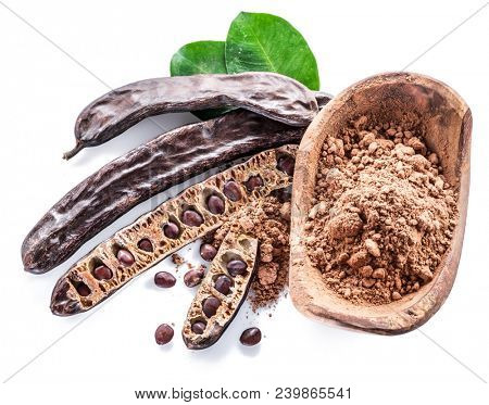 Carob pods and carob powder in the wooden bowl. White background.