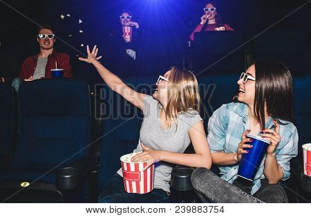 Funny Picture Of Girls Sitting Together In Cinema Hall. They Are Looking At The Boy That Sits Behind
