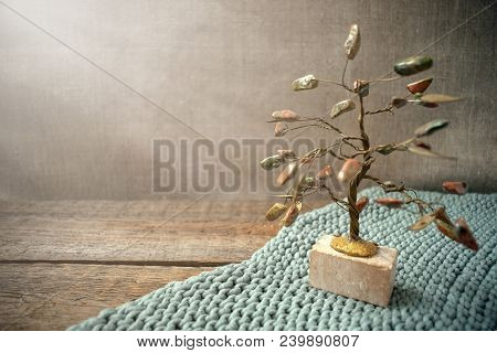 Jasper And Wire Tree In The Rays Of Light On Knitted Fabric And Old Vintage Textured Wooden Backgrou