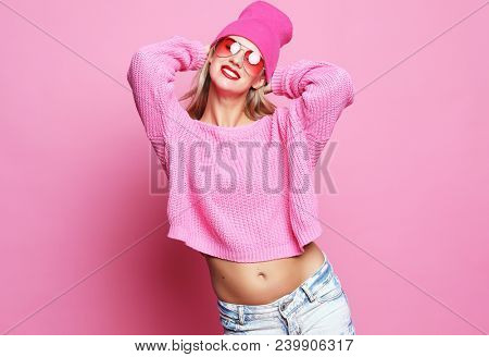 Stylish  fashion portrait of trendy casual young woman in pink pulover and  hat,  posing over pink background. Hipster style.