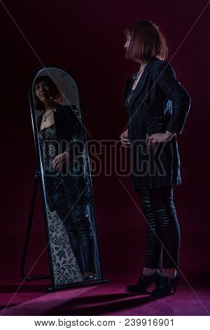 Confident Ugly Woman Wearing Black Suit Stands Near Mirrow In Front Of Camera On Stage With Crimson 