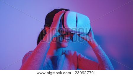 Woman look though VR device with blue and red light 