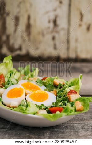 High Angle View Of A Nutritious Vegetable Salad With Boiled Egg Slices, Served On A White Plate On T