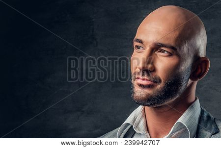 Positive Shaved Head Male Dressed In A Grey Suit Over Dark Grey Background.