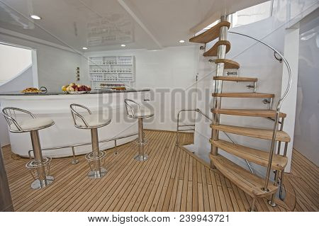 Wooden Curved Spiral Staircase And Bar Area On Sundeck Of Large Luxury Motor Yacht