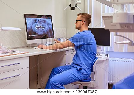 Male Dentist Looking At Teeth X-ray On The Computer In A Dentist Office.