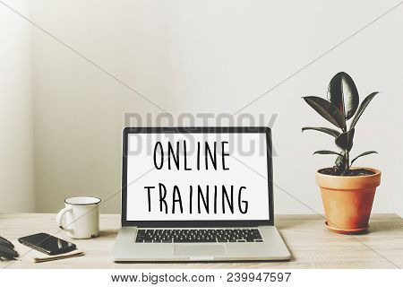 Online Training Text On Laptop Screen On Wooden Desktop With Phone, Notebook, Coffee And Plant. Busi