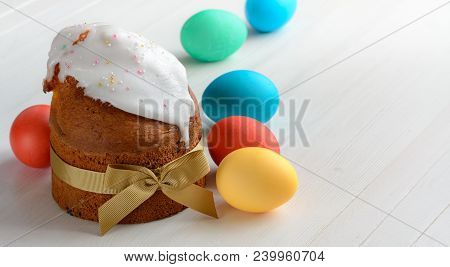 Colorful Easter Eggs And Easter Cake On White Wooden Table.