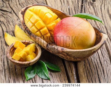 Mango fruit and mango cubes on the wooden table.