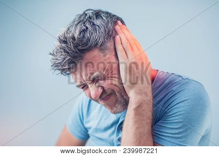 Male Having Ear Pain Touching His Painful Head Isolated On Gray Background