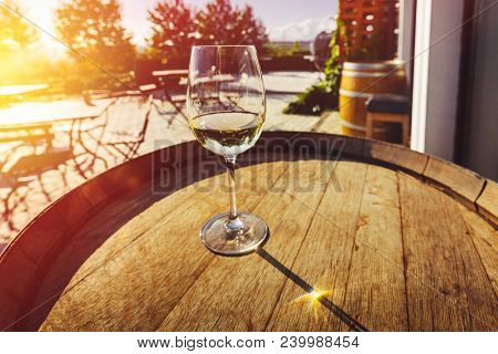 A Glass Of Wine Stands On A Wine Barrel Against The Background Of The Morning Landscape