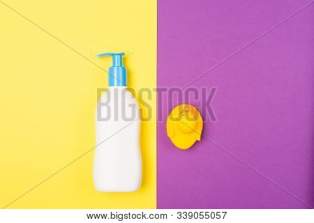 Flat Lay Photography Baby Bath Products. Body Cream And Rubber Duck On A Contrast Yellow And Purple 
