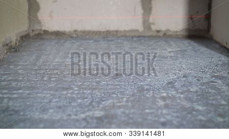 The Hand Of A Man Holding A Roller And Puts Primer On Concrete Floor. Primer For Concrete Floors