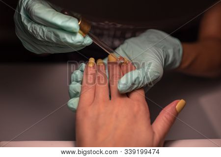 A Manicure Hand With A Nail Lies On A Manicure Hand In Blue Hygienic Gloves.hands On The Manicure Of