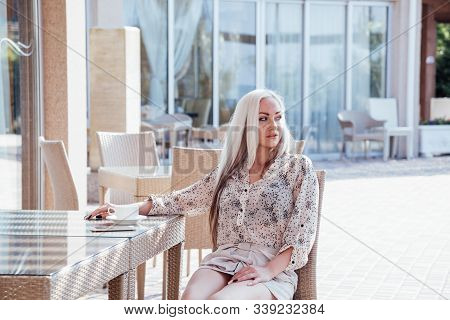 Blonde Girl Sitting At The Beach Restaurant Coffee