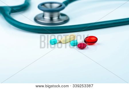 Stethoscope With Blue-white Capsule, Red Soft Gel Capsule Pills, And Red Round Tablets On Doctor Tab