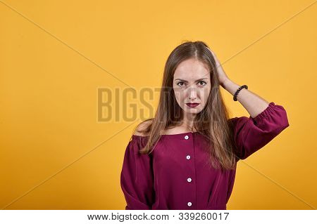 Ginger Girl Over Isolated Orange Background In Burgundy Bluse Unsatisfied Holding Hand On Head