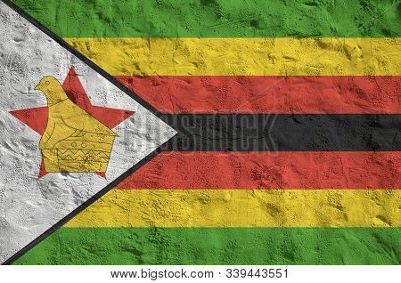 Zimbabwe Flag Depicted In Bright Paint Colors On Old Relief Plastering Wall. Textured Banner On Roug