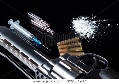 A Syringe With Ampoules, White Powder, A Five-dollar Bill With Bullets And A Gun Lying On A Black Gl